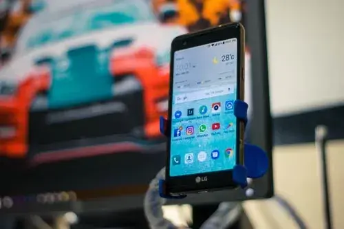 LG smartphone held in a stand showing Android home screen with app icons, representing native Android app development.